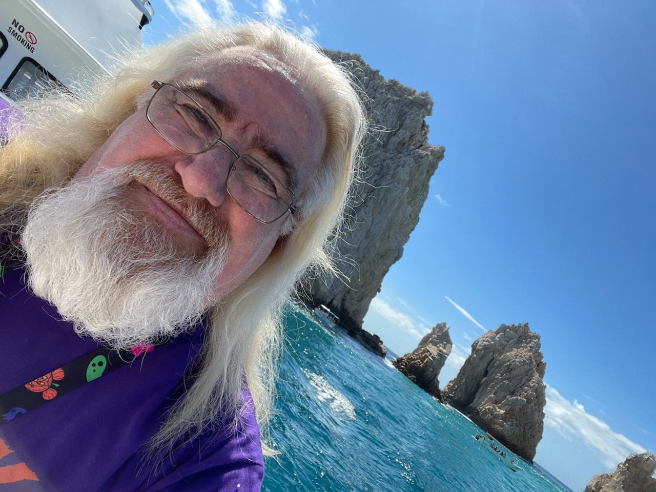 Lawrence Brody on a boat excursion in Cabo San Lucas with turquoise ocean and rock formations