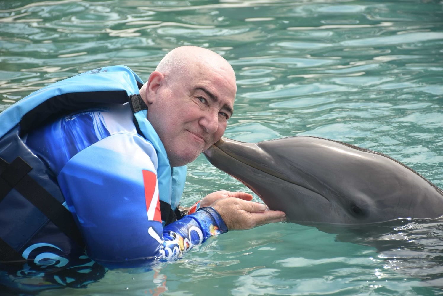 Lawrence Brody cheek-to-snout with a bottlenose dolphin during a swim experience