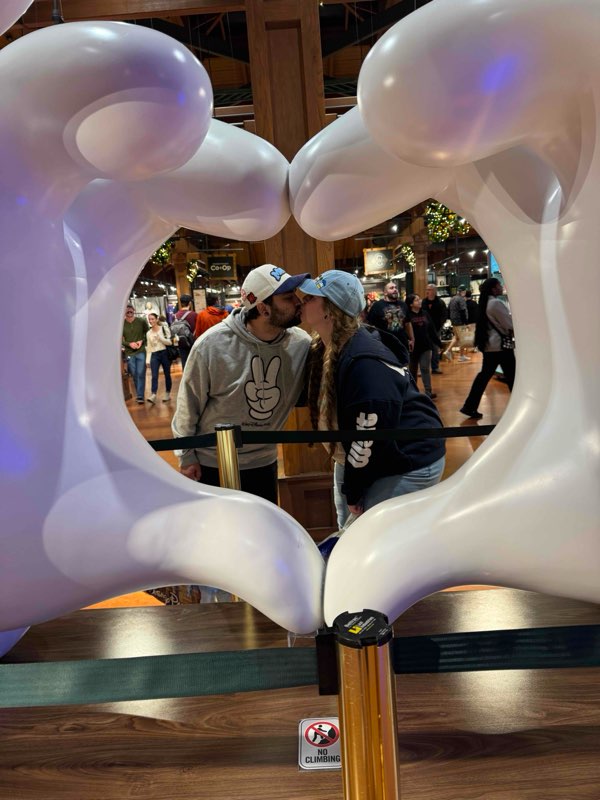 Couple kissing inside the heart-shaped hands sculpture at Disney Springs