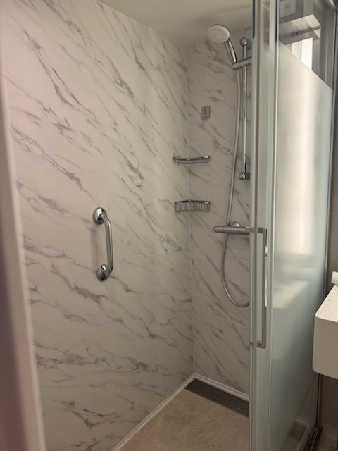 Marble walk-in shower with rain shower head in the Norwegian Jewel suite bathroom