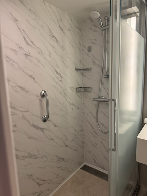 Marble walk-in shower with rain shower head in the Norwegian Jewel suite bathroom