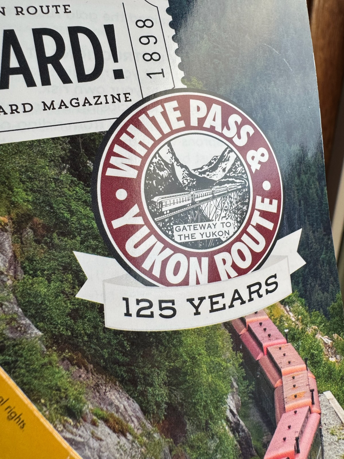 White Pass and Yukon Route magazine cover with train in the mountains and 125 Years badge