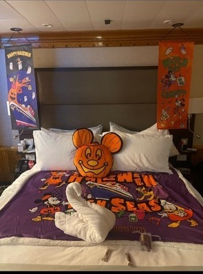 Disney Wonder Halloween on the High Seas Concierge 1 Bedroom Suite with purple Halloween blanket, Mickey jack-o-lantern pillow, and towel animal
