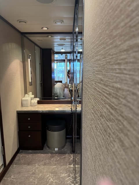 Vanity and dressing area with marble countertop and folded towels in the Norwegian Jewel suite