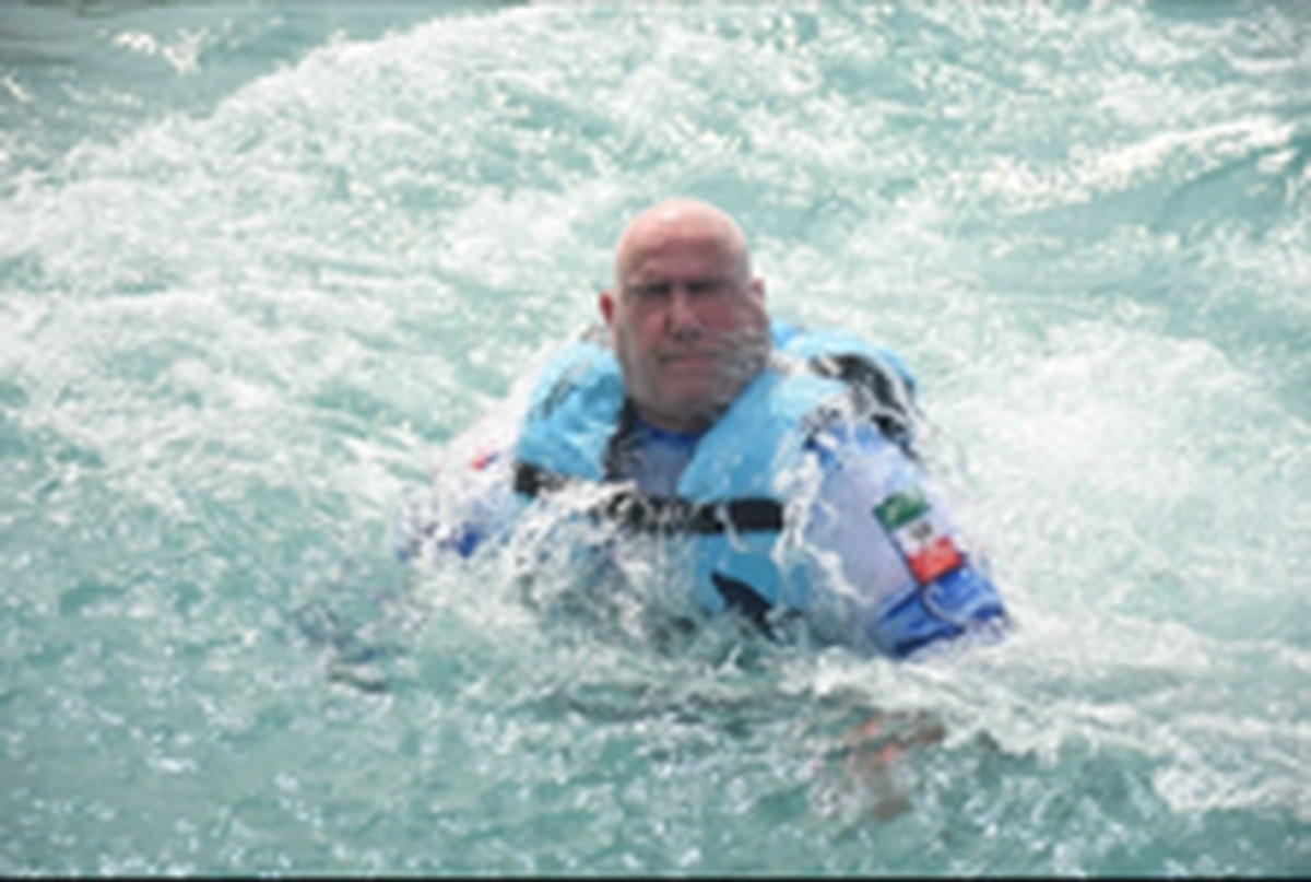 Lawrence Brody in a life vest, partially submerged in churning water as dolphins push him on a Disney Fantasy Caribbean excursion — sequence 1 of 3