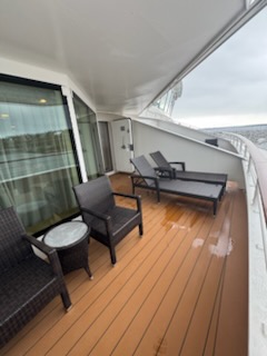 Forward-facing private balcony on the Norwegian Jewel with lounge chairs, wicker seating, and open ocean horizon