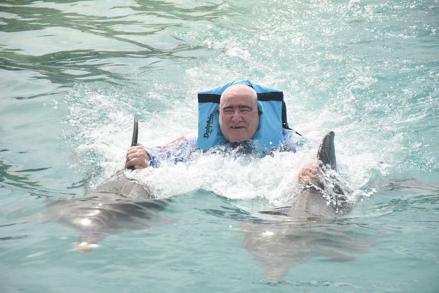 Lawrence Brody being towed by two dolphins in the Caribbean