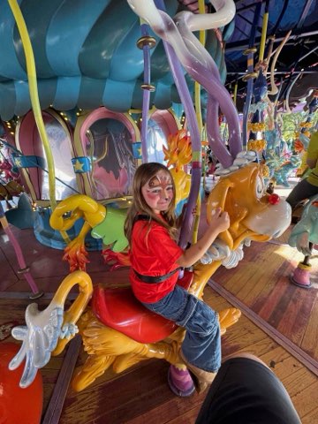 Granddaughter smiling on a whimsical carousel ride at Disney World